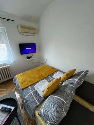 a bedroom with a bed and a tv on the wall at Apartman Stevan in Pančevo