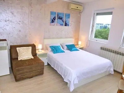 a bedroom with a bed with blue pillows and a chair at Arena Dream Studio in Belgrade