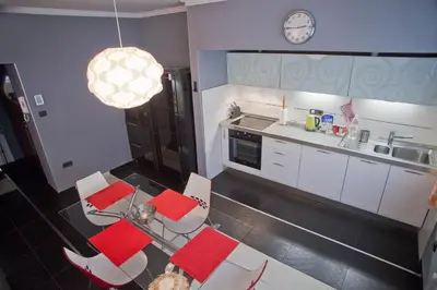 a kitchen with a table and chairs and a clock at Angel Apartment in Belgrade