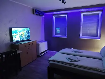 a purple room with a bed and a flat screen tv at Left Coast studio apartment in Belgrade