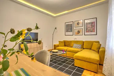 a living room with a yellow couch and a table at Belgrade City Center Modern Apartment in Belgrade