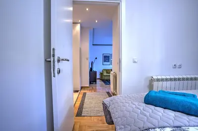 a bedroom with a bed and a door leading to a hallway at Belgrade City Center Modern Apartment in Belgrade