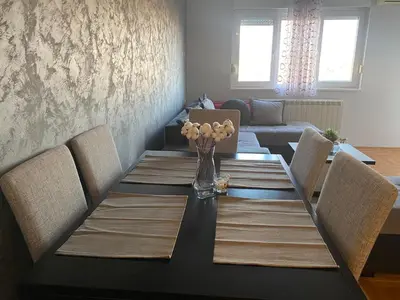 a dining room table with chairs and a vase of flowers at Malina 24 in Belgrade