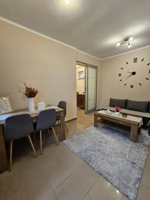 a living room with a table and a clock on the wall at Prenoćište Lana in Novi Banovci