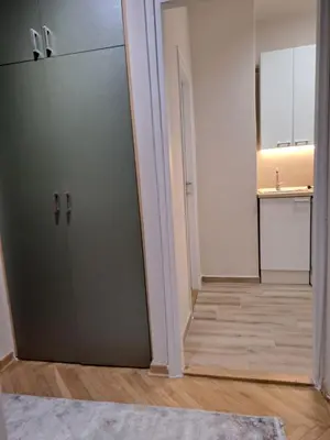 an empty room with a door and a kitchen at Ema's Cosy apartment in Belgrade