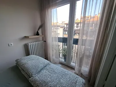 a bedroom with a bed and a large window at Ema's Cosy apartment in Belgrade