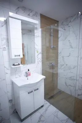 a white bathroom with a sink and a shower at Apartman Ub in Ub