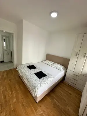 a bedroom with a white bed and a wooden floor at Apartman Ub in Ub