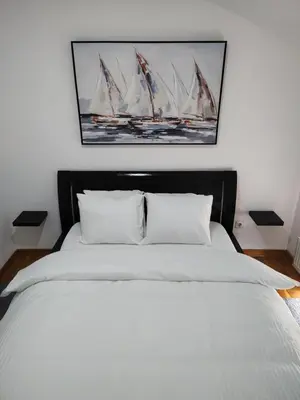 a bedroom with a bed with a painting of sailboats at Apartman Visnjica in Rospi Ćuprija