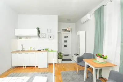 a kitchen and dining room with white cabinets and a table at Studio 91 with Great WI-FI and free parking in Belgrade