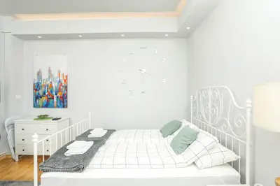 a white bedroom with a bed and a white cabinet at Studio 91 with Great WI-FI and free parking in Belgrade