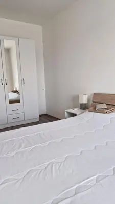 a white bed in a white bedroom with a mirror at Banjica Stan 203 in Belgrade