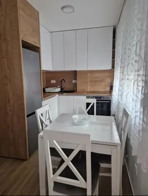 a white kitchen with a white table and chairs at Stan na dan Beograd in Mirijevo