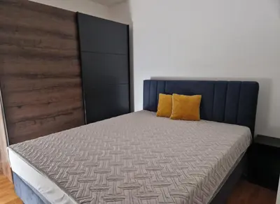 a bed with a blue headboard and yellow pillows on it at Stan na dan Beograd in Mirijevo