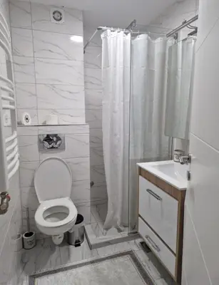 a white bathroom with a toilet and a shower at Stan na dan Beograd in Mirijevo