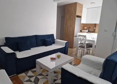 a living room with a blue couch and a table at Stan na dan Beograd in Mirijevo