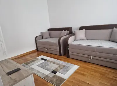 a living room with two couches and a rug at Stan na dan Beograd in Mirijevo