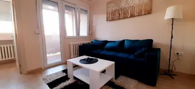 a living room with a blue couch and a table at Apartman Studenjak in Tošin Bunar