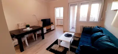 a living room with a blue couch and a table at Apartman Studenjak in Tošin Bunar