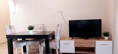 a dining room table with a television and chairs at Apartman Studenjak in Tošin Bunar