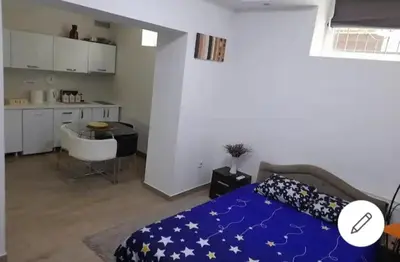 a bedroom with a blue bed and a kitchen at XENIA2 in Belgrade