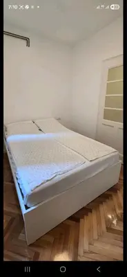 a white bed in a room with a wooden floor at Admiral Gate in Belgrade