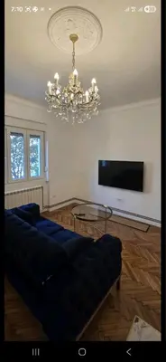 a living room with a blue couch and a chandelier at Admiral Gate in Belgrade