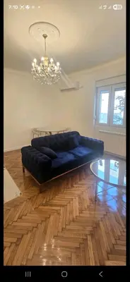 a blue couch in a living room with a chandelier at Admiral Gate in Belgrade