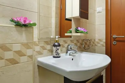 a bathroom with a sink and a mirror and pink flowers at Apartment SEIF 1 in Belgrade