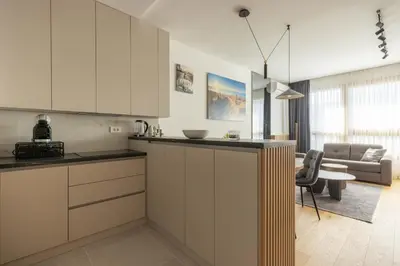 a kitchen with white cabinets and a living room at N65 LUX Apartment in Belgrade