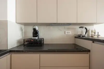 a kitchen with white cabinets and a black counter top at N65 LUX Apartment in Belgrade