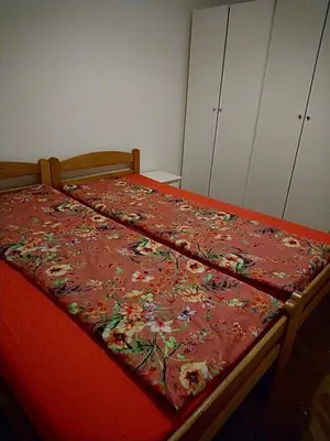 a bed with a red bedspread with flowers on it at Stan Ledine 65m2 in Novi Beograd