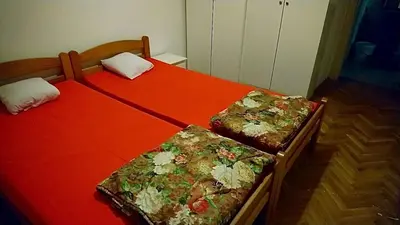 two beds in a bedroom with red sheets and flowers at Stan Ledine 65m2 in Novi Beograd