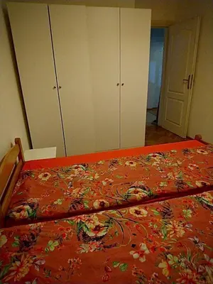 a bed with an orange blanket with flowers on it at Stan Ledine 65m2 in Novi Beograd