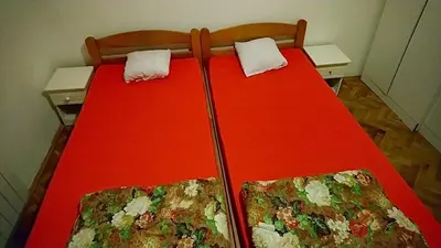 a red bed with two chairs in a room at Stan Ledine 65m2 in Novi Beograd