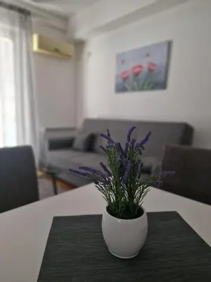 a white vase with purple flowers sitting on a table at Stan Na Dan 022 in Inđija
