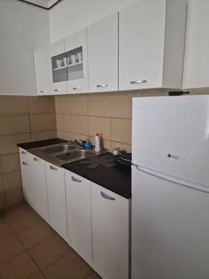 a white kitchen with a sink and a refrigerator at Stan Na Dan 022 in Inđija