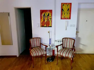 two chairs and a table in a room with paintings at Lavanda in Belgrade