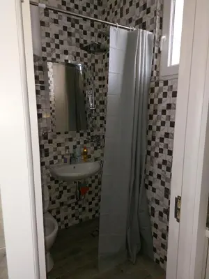 a bathroom with a sink and a shower with a mirror at Tiny Apartment in Belgrade