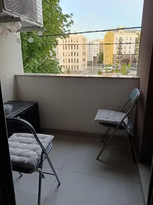 a balcony with two chairs and a table and a window at Zemun residence in Novi Grad