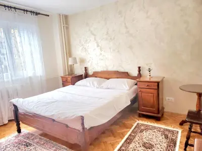 a bedroom with a bed and a table and a window at Erste City Apartment in Sajmište