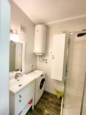 a bathroom with a sink and a washing machine at Erste City Apartment in Sajmište