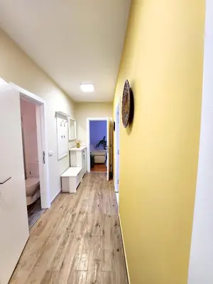 a hallway with a yellow wall and wooden floors at Erste City Apartment in Sajmište