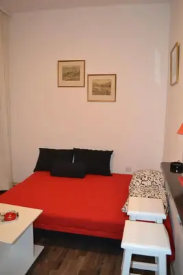 a red bed in a small room with a table at BelgradeCity center-Lekic apart 1 in Belgrade