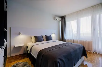 a bedroom with a bed and a large window at Victor Nest Double Room Apartment in Belgrade