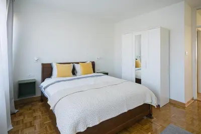 a white bedroom with a large bed with yellow pillows at Victor Nest Double Room Apartment in Belgrade