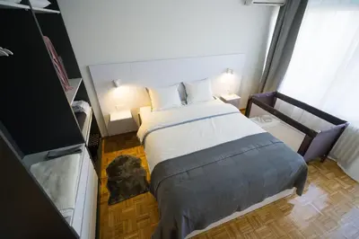 a small bedroom with a bed and two lamps at Victor Nest Double Room Apartment in Belgrade