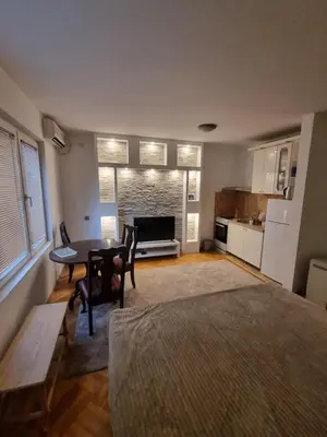 a living room with a table and a kitchen at Modern apartment - quiet street in Belgrade