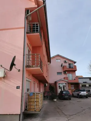 a pink building with balconies and cars parked in a parking lot at Studio Lena in Belgrade