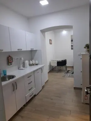 a kitchen with white cabinets and a wooden floor at XENIA1 in Belgrade